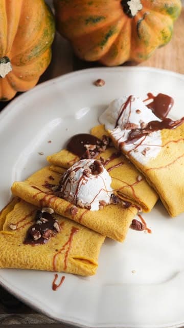 Crepas con chocolate, plátano y coco rallado sobre un plato blanco